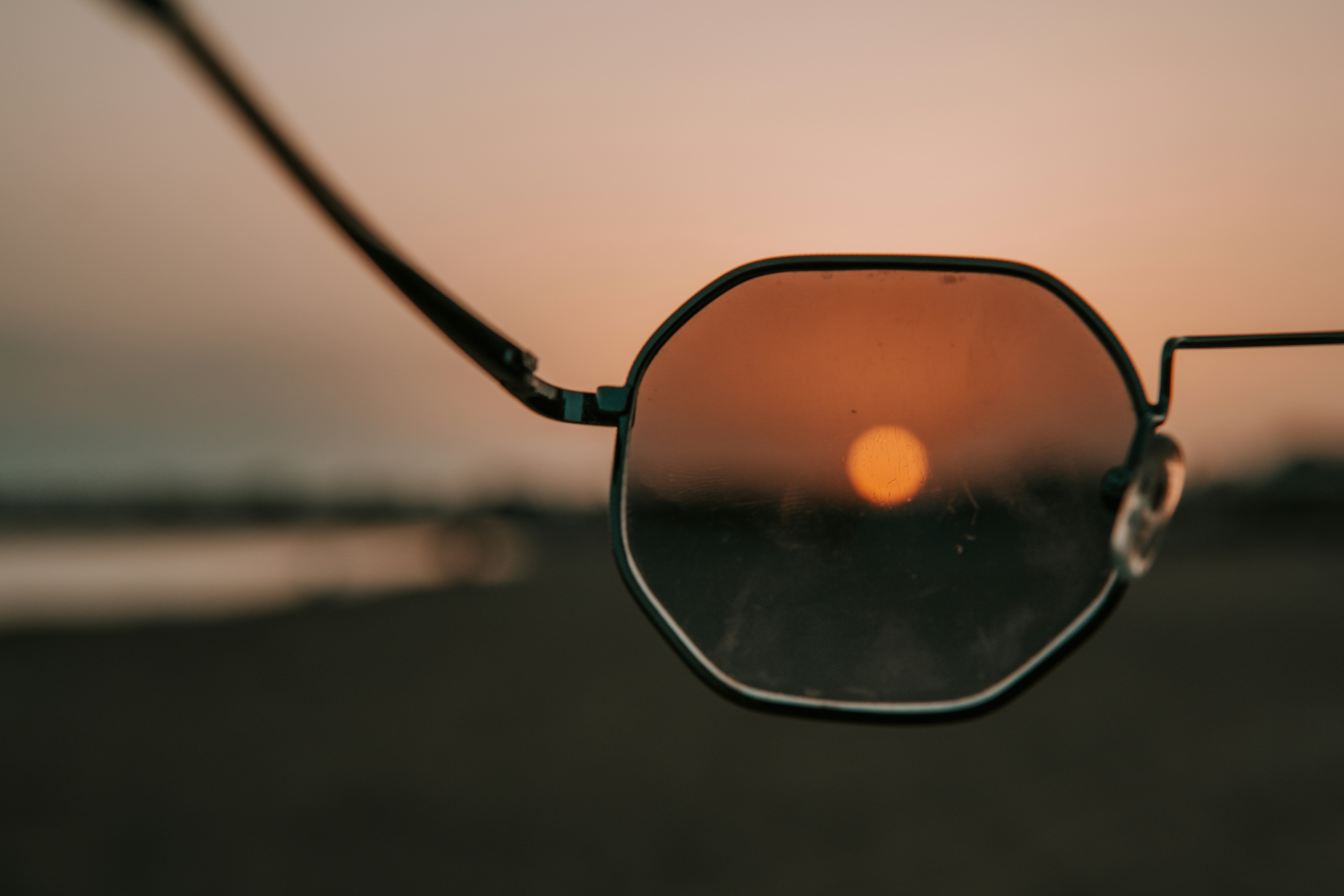 black framed sunglasses on beach during sunset